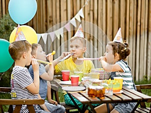 Cute funny nine year old boy celebrating his birthday with family or friends with homemade baked cake in a backyard. Birthday