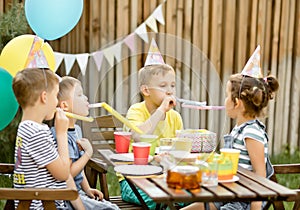 Cute funny nine year old boy celebrating his birthday with family or friends with homemade baked cake in a backyard. Birthday