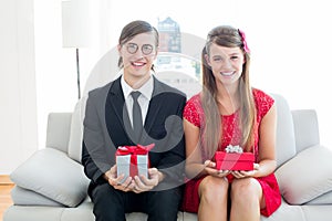 Cute geeky couple smiling and holding gift