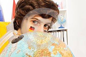 Cute German schoolboy hiding behind the globe