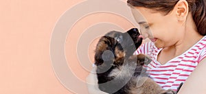 Cute German shepherd puppy kissing woman`s nose
