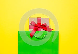 Cute gift in beautiful green shopping bag on wonderful yellow ba