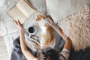 Hygge concept with cat, book and coffee in the bed photo