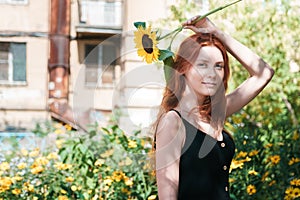 Cute ginger girl posing with sunflower outdoor