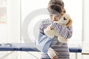 Cute girl with arm brace and teddy bear