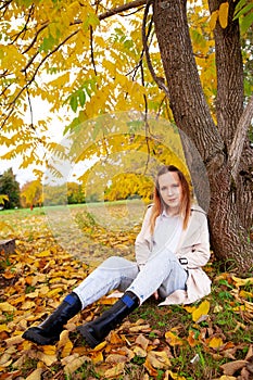 Cute girl on  autumn day against  background of yellow leaves