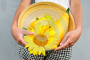 Cute girl with autumn harvest at the wall. Harvesting, yellow sunflower, pepper and pumpkin