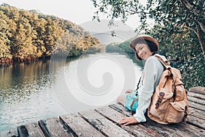 Cute girl backpacking and sitting on the wood plank resting