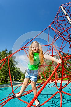 Cute girl balancing on red rope of web outside