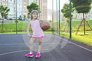 Cute girl with a basketball ball on the playground. Healthy lifestyle and sport concepts