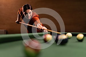 Cute girl beautiful playing billiard balls on table in nightclub. Billiards concept