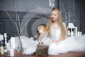 Cute girl with blond hair in a white dress with a white owl