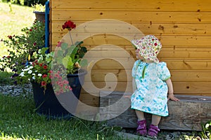 Cute girl in blue dress sitting in front children playhouse