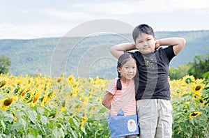 Cute girl and boy hugging fun in sunflower field