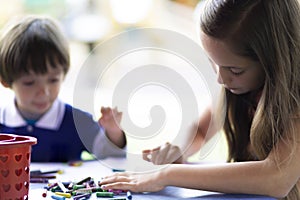 Cute Girl and Boy Sitting at his Desk Painting