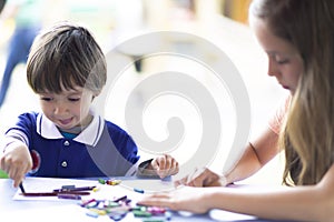 Cute Girl and Boy Sitting at his Desk Painting