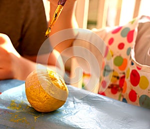 Cute girl with a brush for painting paints the salted dough pots at home. Creative creativity concept for children. Childhood