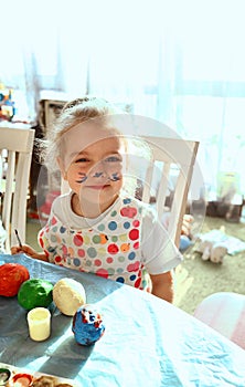 Cute girl with a brush for painting paints the salted dough pots at home. Creative creativity concept for children. Childhood