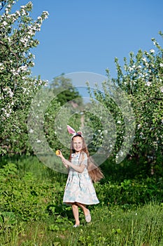 Cute girl with bunny ears on Easter day. A girl is chasing Easter eggs in the garden