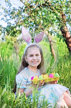 Cute girl with bunny ears on Easter day. A girl is chasing Easter eggs in the garden