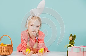 Cute girl in bunny ears on Easter day. Girl holding painted eggs.