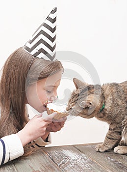 Cute girl celebrates holiday with cake and cat.