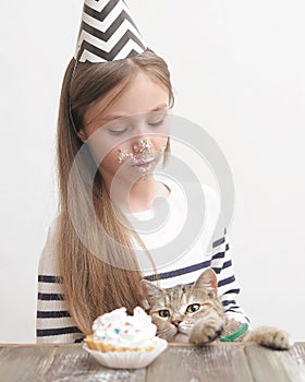 Cute girl celebrates holiday with cake and cat.