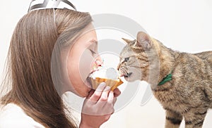 Cute girl celebrates holiday with cake and cat.