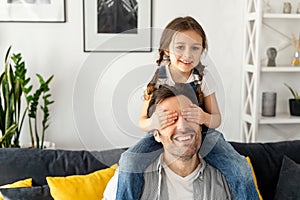 Cute girl closed eyes to her father. Loving father carrying his little toddler daughter on the shoulders sitting on the