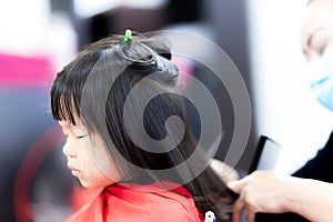 Cute girl closed her eyes and covered veil on body in barber shop. Child underwent hairstyling for their beauty.