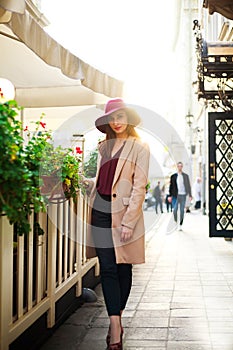 Cute girl in coat on street tourist town with flowers on sunset