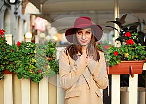 Cute girl in coat on street tourist town with flowers on sunset