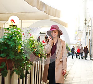Cute girl in coat on street tourist town with flowers on sunset