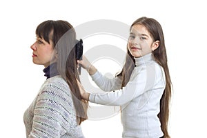 Cute girl combing her hair and her mother smiling