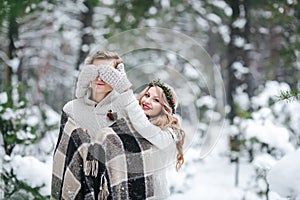 Cute girl covering boyfriend`s eyes by her knitted mittes. Winter wedding. Artwork.