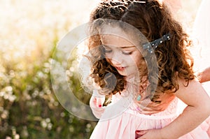 Cute girl with curls in the hands of mom