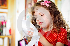 Cute girl cutting paper with scissors