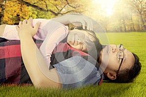 Cute girl and dad lying on the grass at park