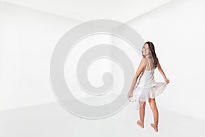Cute girl dances happily in an empty white room