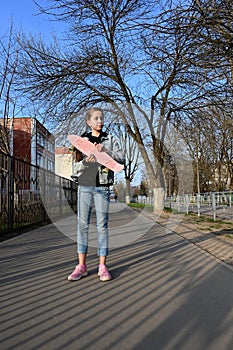 cute girl in denim and pink sneakers holds a penny board, a longboard . International Skateboarding Day.