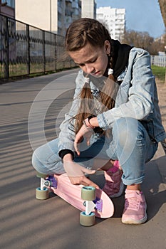 cute girl in denim and pink sneakers and penny board, longboard . International Skateboarding Day.
