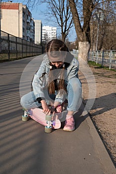 cute girl in denim and pink sneakers and penny board, longboard . International Skateboarding Day.