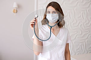 Cute girl doctor in a medical mask shows a stethoscope