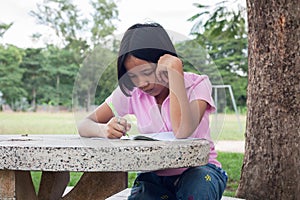 Cute girl doing homework in the park