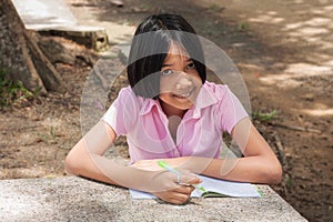 Cute girl doing homework in the park