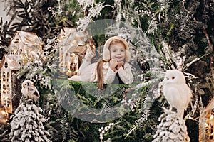 Cute girl in earmuffs resting in Christmas decorations.