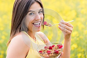 Cute girl eating healthy cereal breakfast outdoors.