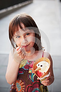 Cute girl eating ice-cream outside