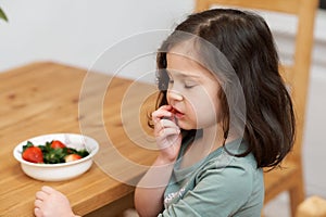 cute girl eating strawberries in the kitchen while chatting with grandma