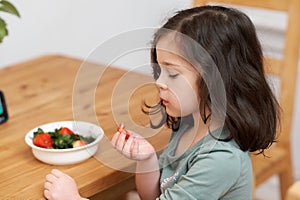 cute girl eating strawberries in the kitchen while chatting with grandma